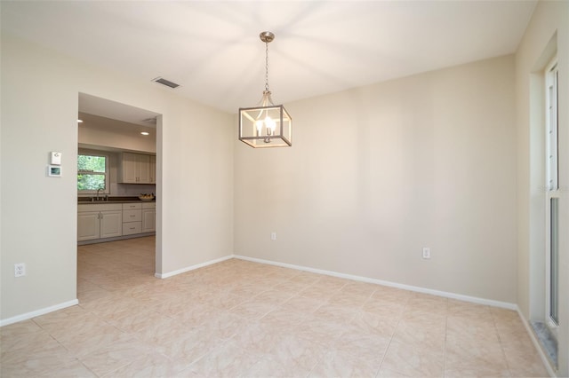 unfurnished room with sink, light tile patterned floors, and an inviting chandelier