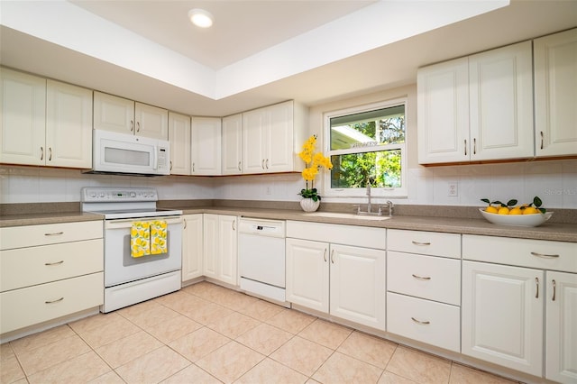 kitchen with sink, tasteful backsplash, white cabinetry, light tile patterned floors, and white appliances