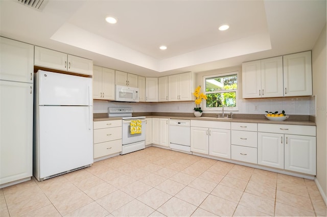 kitchen with sink, white cabinetry, a tray ceiling, white appliances, and backsplash