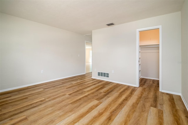 unfurnished bedroom with a closet, a spacious closet, and light hardwood / wood-style flooring