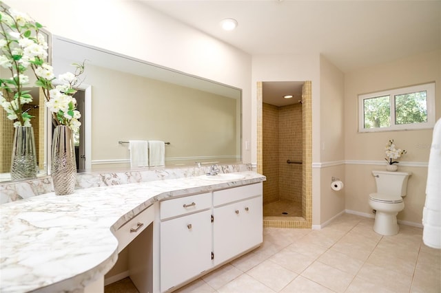 bathroom featuring vanity, tile patterned flooring, toilet, and a tile shower