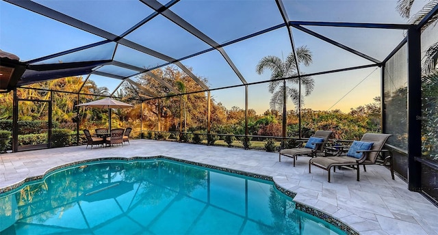 pool at dusk with a lanai and a patio area