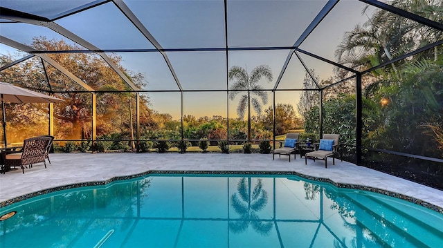 pool at dusk featuring a lanai and a patio area