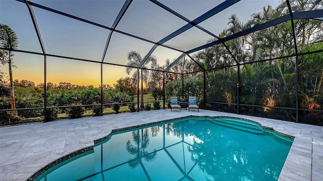 pool at dusk with a lanai and a patio area