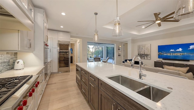 kitchen with sink, appliances with stainless steel finishes, light stone countertops, white cabinets, and decorative light fixtures