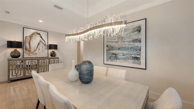 dining room featuring ornamental molding, hardwood / wood-style floors, and a notable chandelier