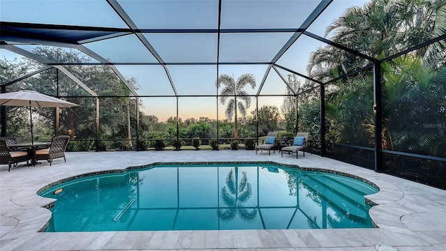 pool at dusk with a patio and glass enclosure