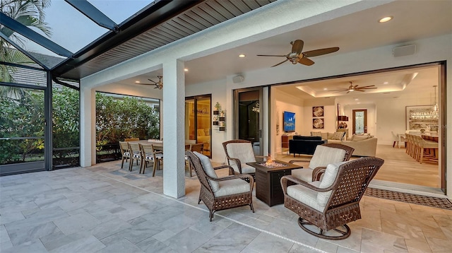 view of patio featuring a lanai, an outdoor living space with a fire pit, and ceiling fan