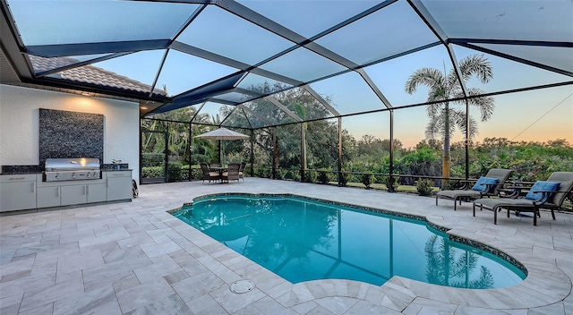 pool at dusk with area for grilling, a lanai, exterior kitchen, and a patio