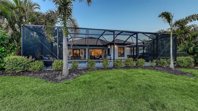 back of property featuring a patio area, a lawn, and glass enclosure