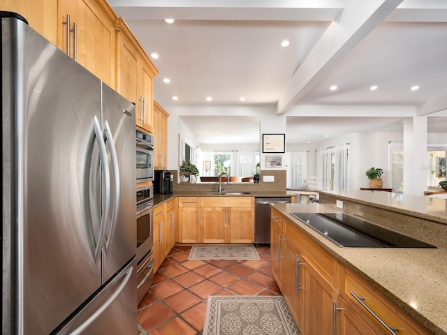 kitchen with sink, appliances with stainless steel finishes, beam ceiling, light stone countertops, and dark tile patterned flooring