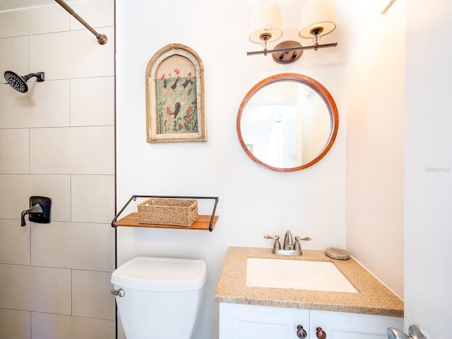 bathroom with vanity, toilet, and a tile shower