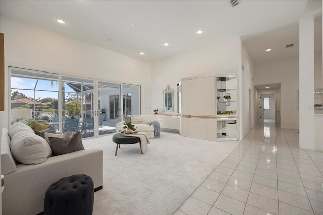 living room with a towering ceiling and light tile patterned floors