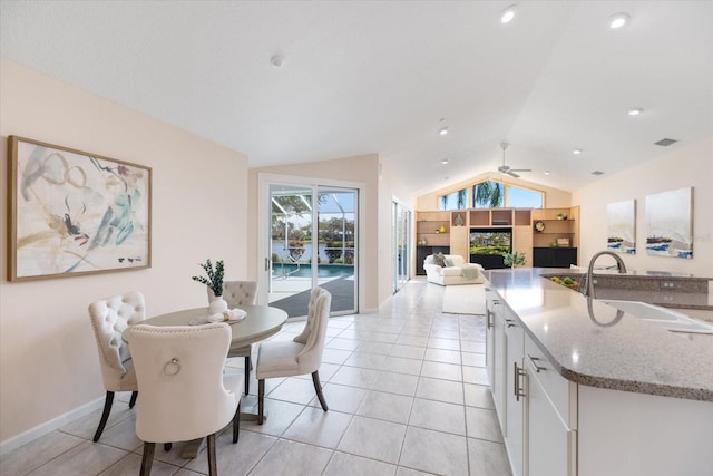 kitchen featuring sink, light stone counters, vaulted ceiling, light tile patterned floors, and white cabinets