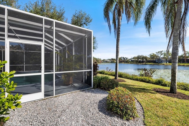 exterior space featuring a water view, glass enclosure, and a lawn