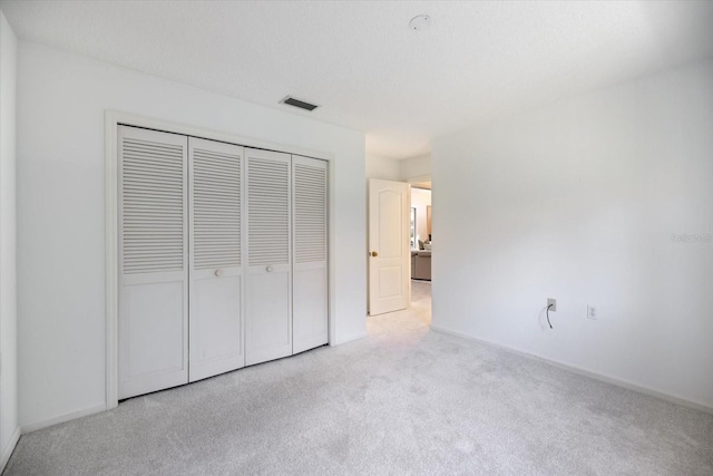 unfurnished bedroom featuring a closet, light carpet, and a textured ceiling