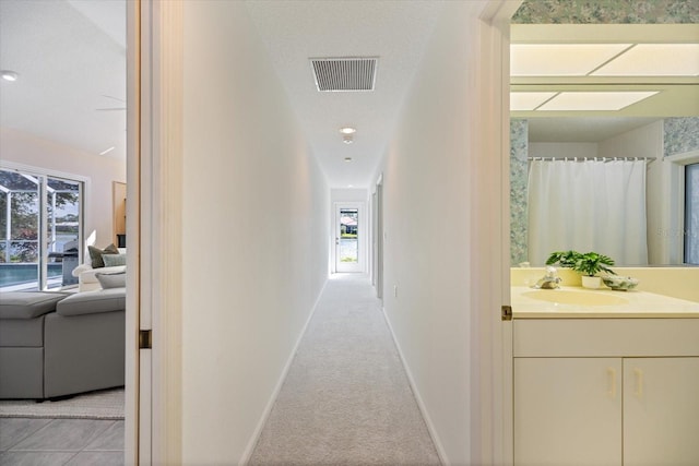 corridor with light colored carpet and sink