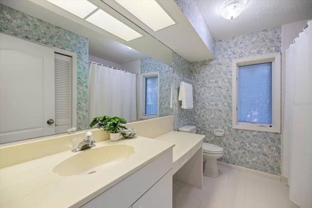 bathroom with vanity, toilet, a skylight, and a textured ceiling