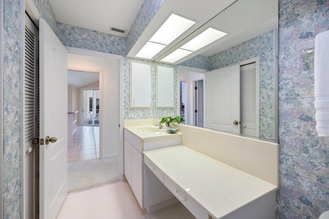 bathroom with vanity, a skylight, and tile patterned floors