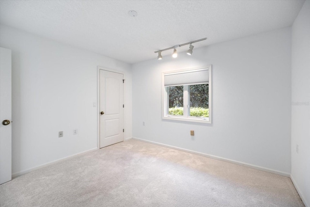 unfurnished room with light colored carpet, track lighting, and a textured ceiling