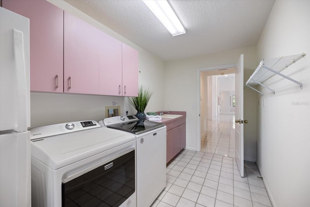 laundry area featuring washer and dryer, cabinets, a textured ceiling, and light tile patterned floors