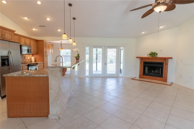 kitchen with light stone counters, stainless steel appliances, light tile patterned floors, lofted ceiling, and ceiling fan