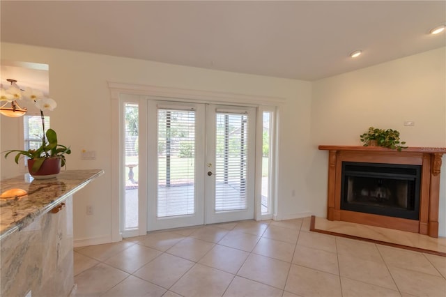 entryway featuring a fireplace, light tile patterned floors, french doors, and baseboards