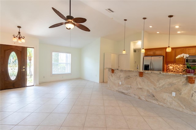 interior space with light tile patterned floors, a ceiling fan, baseboards, visible vents, and high vaulted ceiling