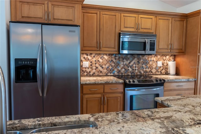 kitchen featuring light stone counters, tasteful backsplash, appliances with stainless steel finishes, and brown cabinetry