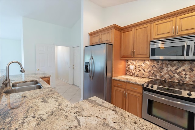 kitchen with decorative backsplash, light stone countertops, stainless steel appliances, and a sink