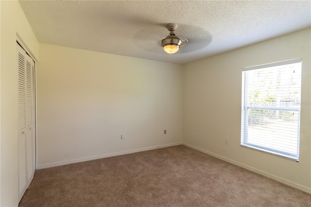 unfurnished bedroom with a textured ceiling, a closet, carpet, baseboards, and ceiling fan