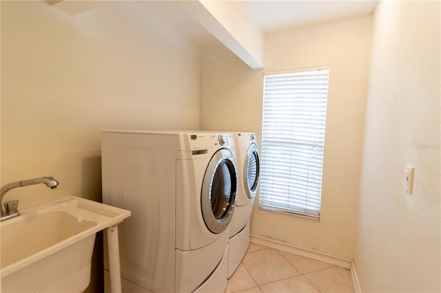 washroom featuring baseboards, laundry area, light tile patterned flooring, a sink, and washer and dryer