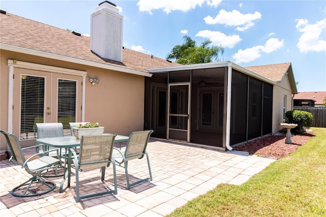 view of patio featuring french doors, fence, outdoor dining space, and a sunroom