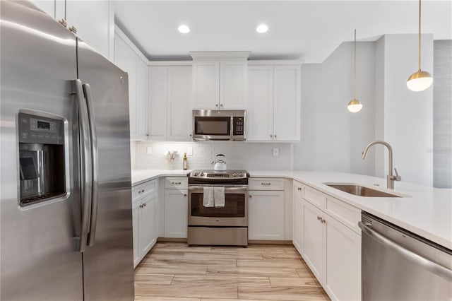 kitchen featuring stainless steel appliances, sink, hanging light fixtures, and white cabinets