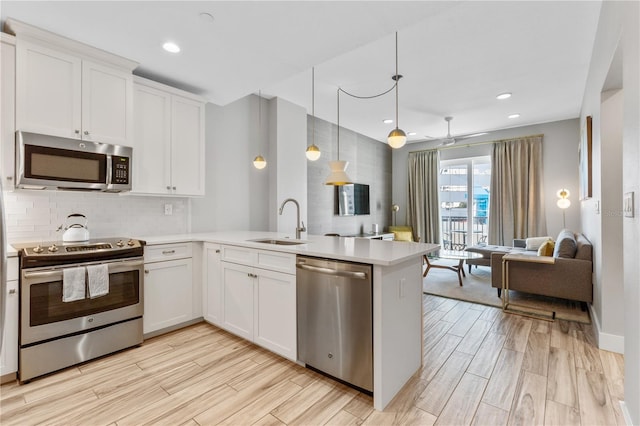 kitchen featuring appliances with stainless steel finishes, pendant lighting, white cabinetry, sink, and kitchen peninsula