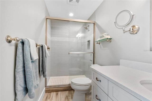 bathroom featuring wood-type flooring, toilet, a shower with shower door, and vanity