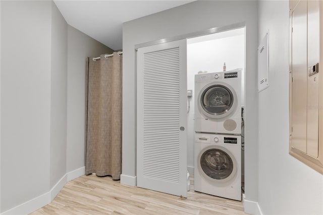 laundry room with stacked washer and clothes dryer and light wood-type flooring