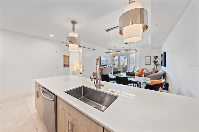 kitchen with sink, hanging light fixtures, light brown cabinets, dishwasher, and a barn door