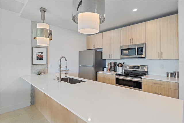 kitchen with appliances with stainless steel finishes, sink, pendant lighting, and light brown cabinetry