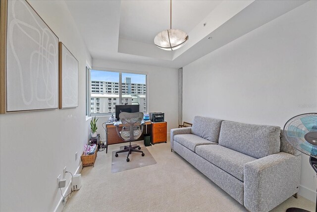 carpeted office space featuring a tray ceiling