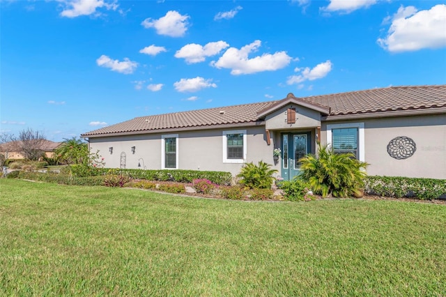 view of front of property featuring a front yard, a tile roof, and stucco siding