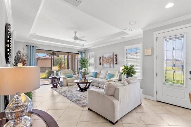 living area with light tile patterned floors, a tray ceiling, visible vents, and crown molding