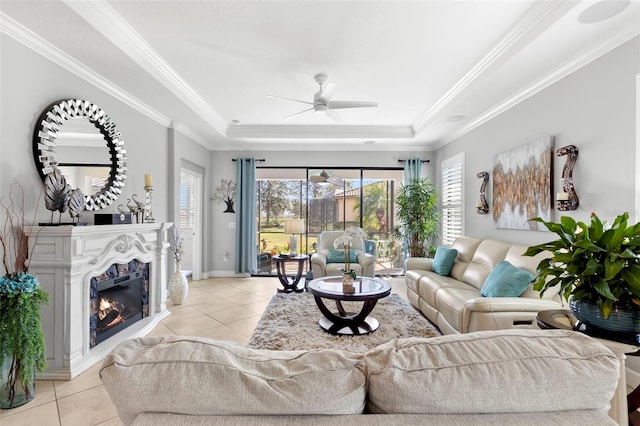 living area with a wealth of natural light, a raised ceiling, and a glass covered fireplace