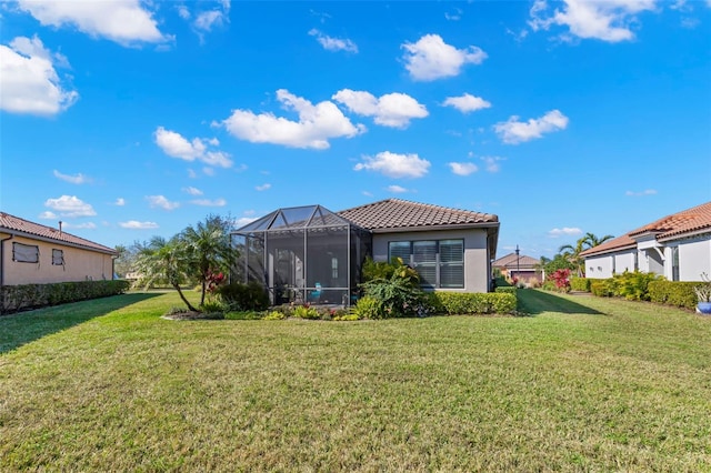 back of house featuring a lanai, stucco siding, a tiled roof, and a yard