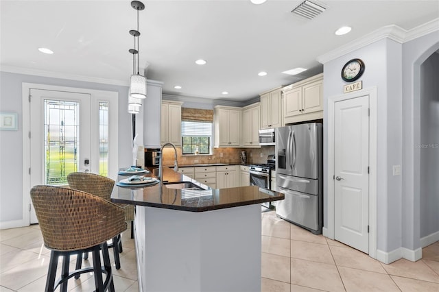 kitchen featuring stainless steel appliances, cream cabinetry, a sink, and visible vents