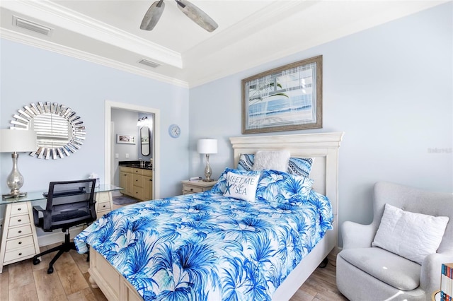 bedroom featuring a tray ceiling, visible vents, crown molding, and wood finished floors