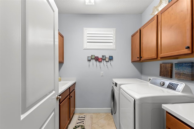 laundry area with cabinet space, baseboards, separate washer and dryer, a sink, and light tile patterned flooring