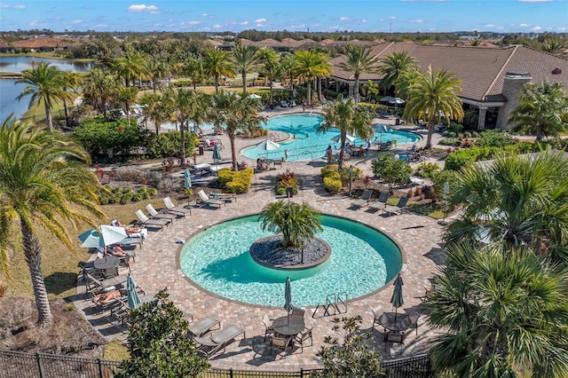 pool with a patio area, a water view, and fence