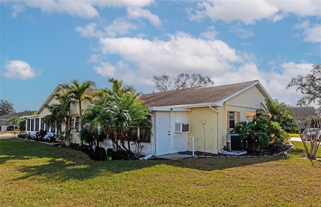 view of property exterior featuring an AC wall unit, a yard, and central AC unit