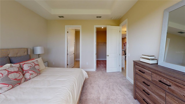 carpeted bedroom with a closet, a walk in closet, and a raised ceiling